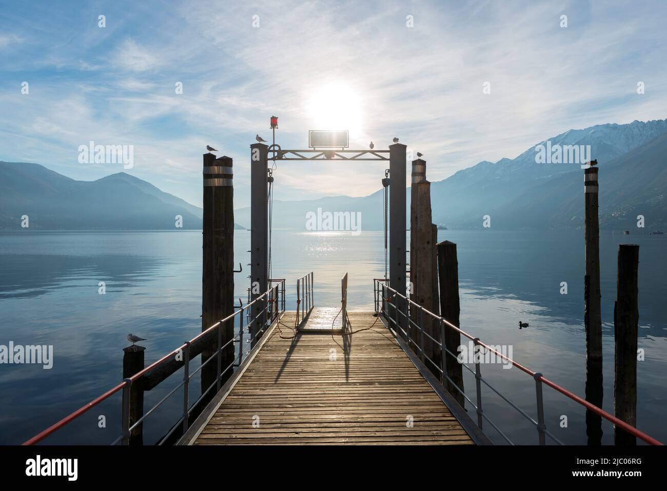Pier am Alpensee Maggiore mit Berg und Sonnenlicht in Ascona, Schweiz. Stockfoto