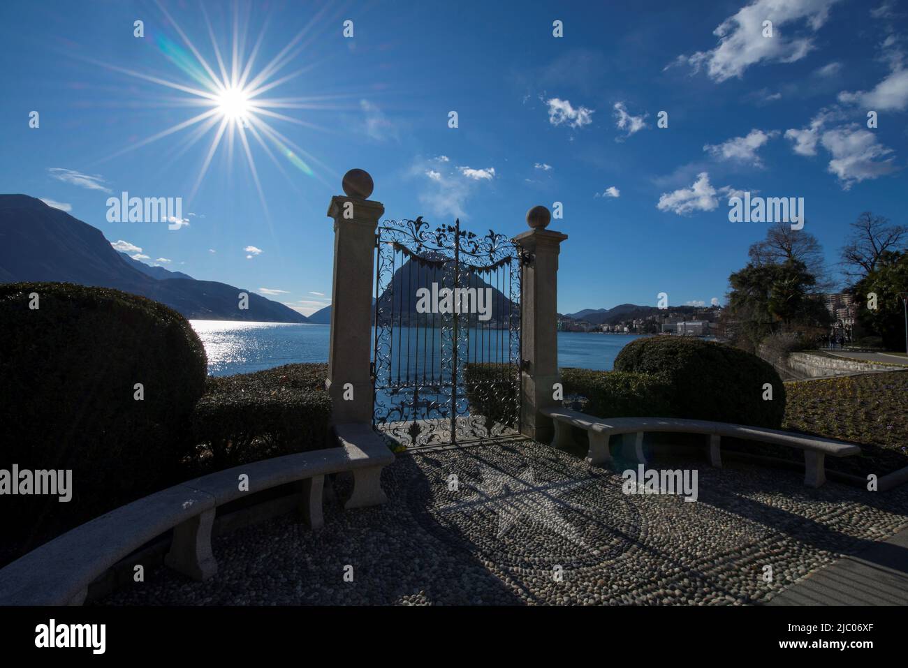 Tor an der Waterfront mit Sunbeam und Alpensee Lugano mit Berg im Tessin, Schweiz. Stockfoto