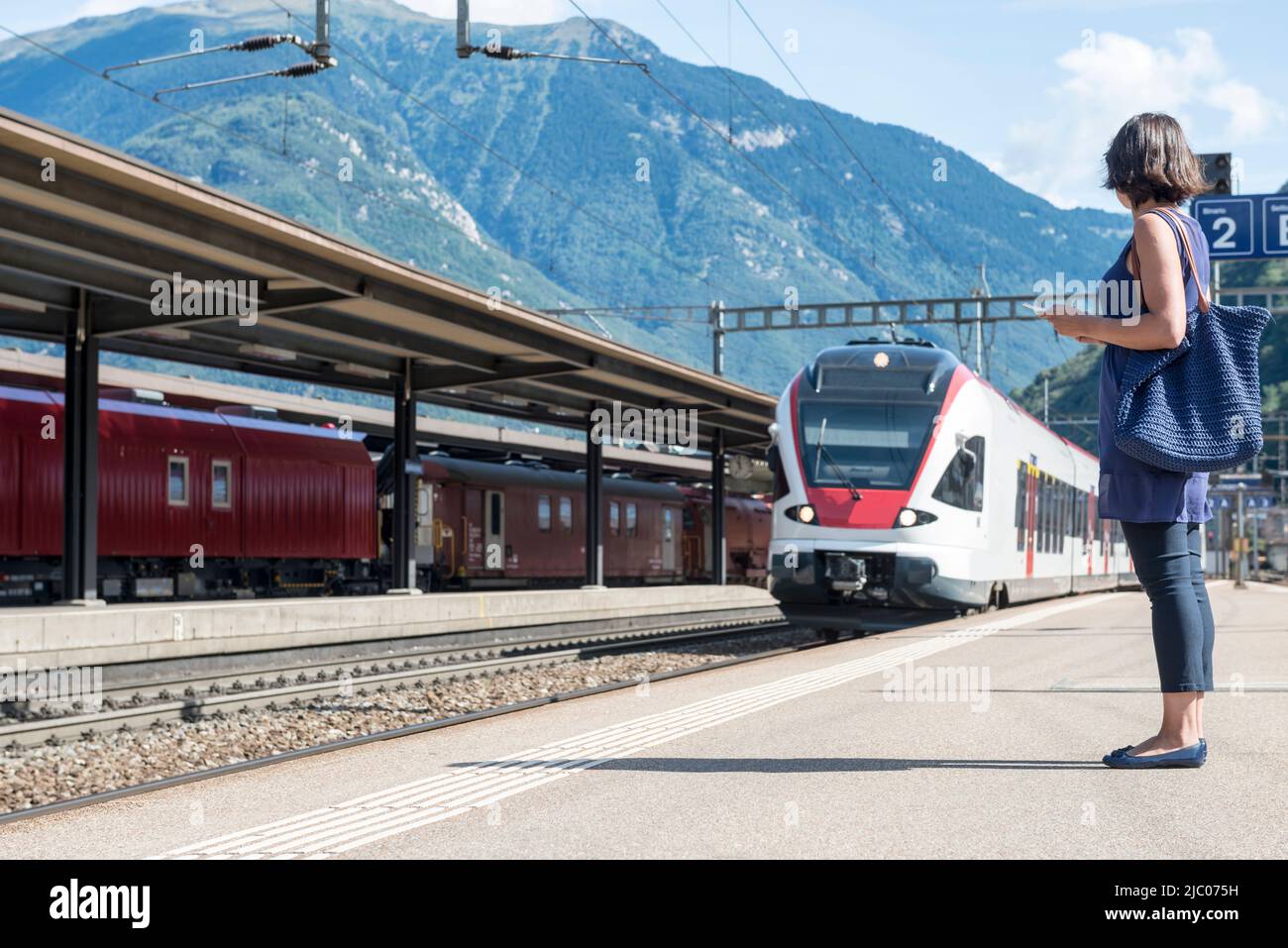 Frau auf dem Bahnhof und ein Zug in Bellinzona, Tessin in der Schweiz. Stockfoto