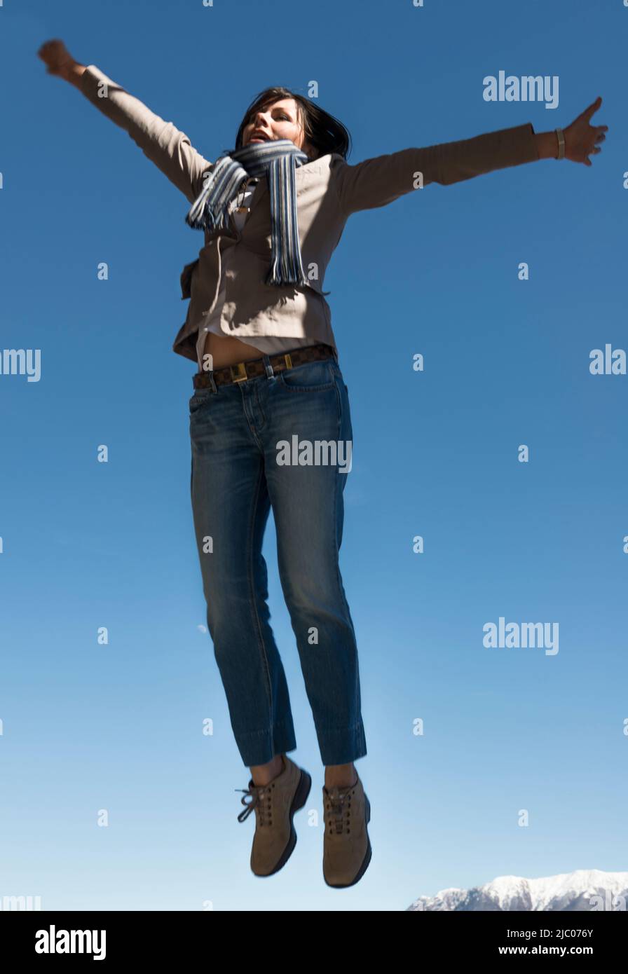 Woman Jumping and with Arms outstrecked with Snow-capped Mountain in Ascona, Schweiz. Stockfoto
