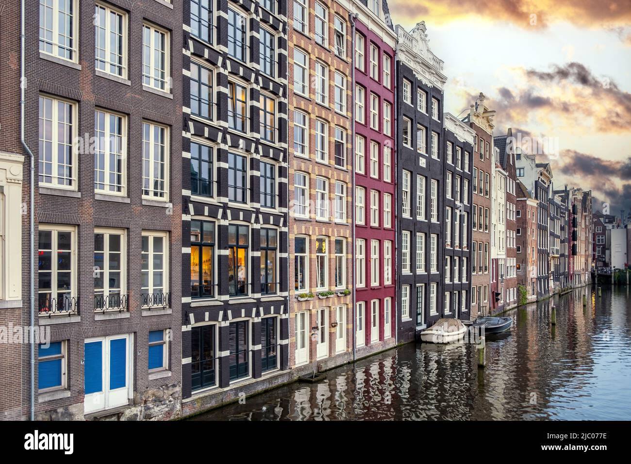 Amsterdamer Häuser, Reflexionen im Kanalwasser, blauer Himmel bei Dämmerung. Touristischer Bezirk Damrak, Niederlande Holland Stockfoto