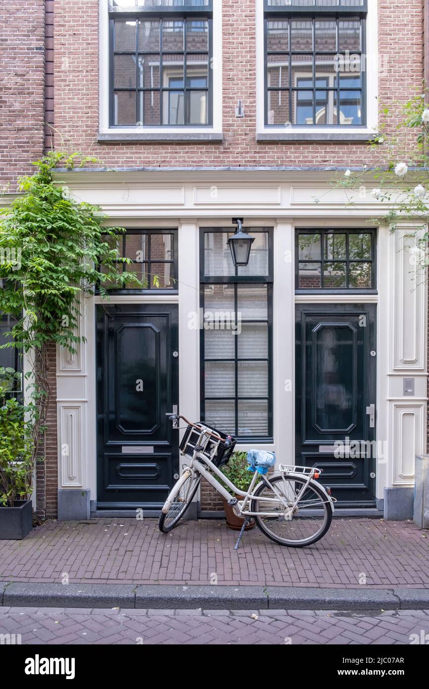 Amsterdamer Haus, traditionelle rote Backsteinfassade, Fahrrad vor dem Haus geparkt. Gebäude in Wohnviertel, Holland Niederlande Stockfoto