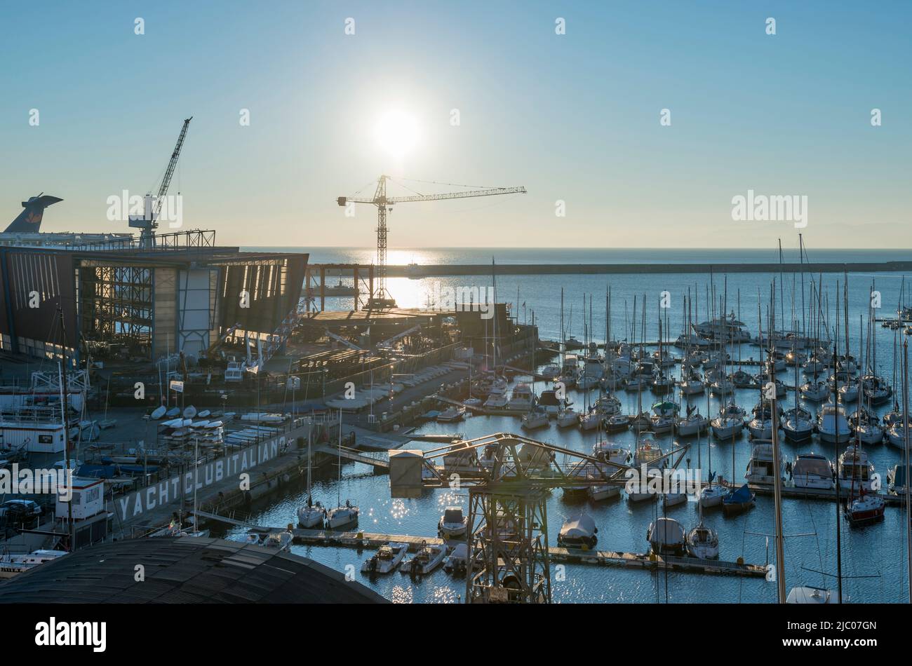 Luftaufnahme über Gebäude im Bau und einem Hafen mit Sonnenlicht auf dem Mittelmeer in Genua, Ligurien in italien. Stockfoto