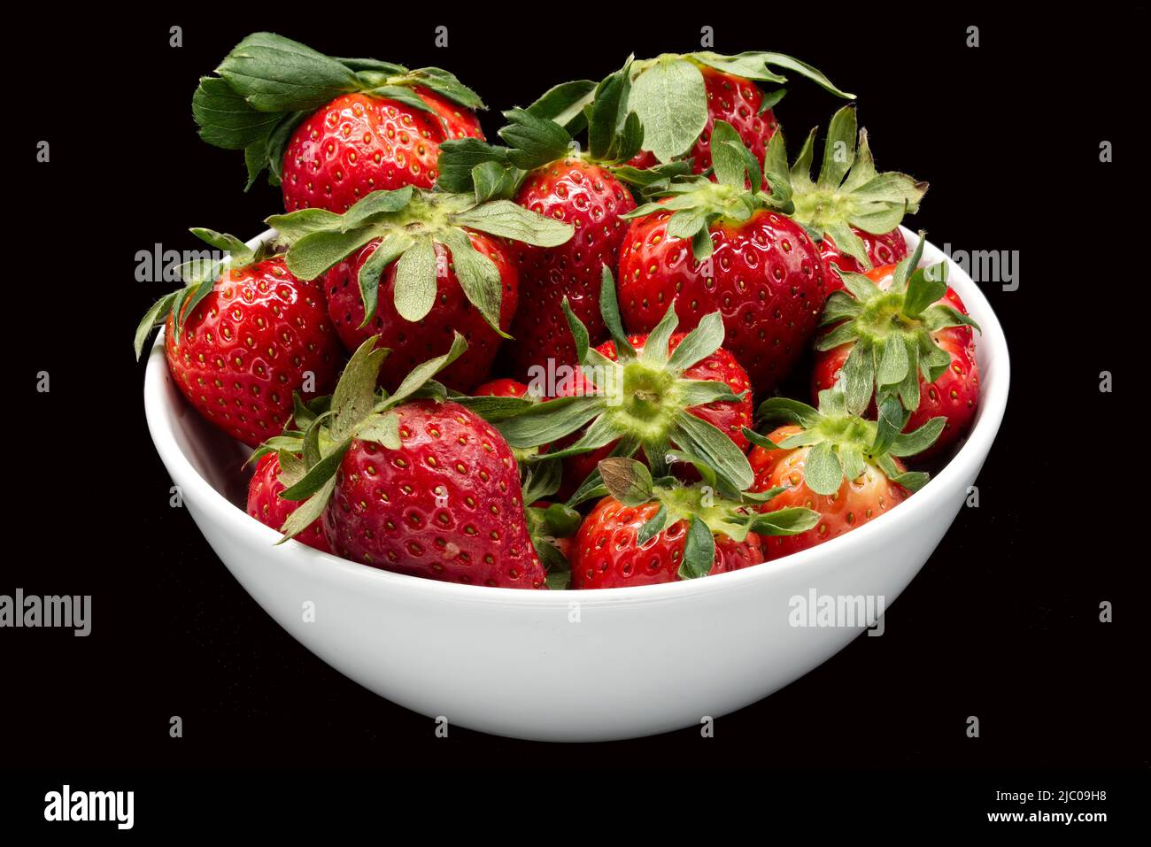 Frische Erdbeere in einer Schale isoliert auf schwarzem Hintergrund. Stockfoto