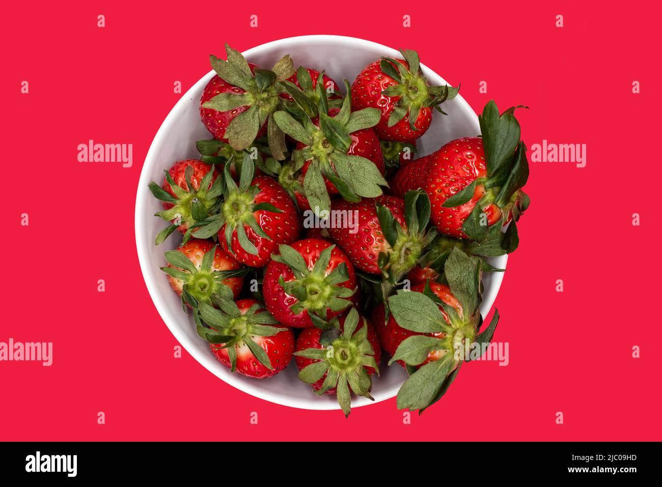 Frische Erdbeere in einer Schale isoliert auf rotem Hintergrund. Draufsicht Stockfoto