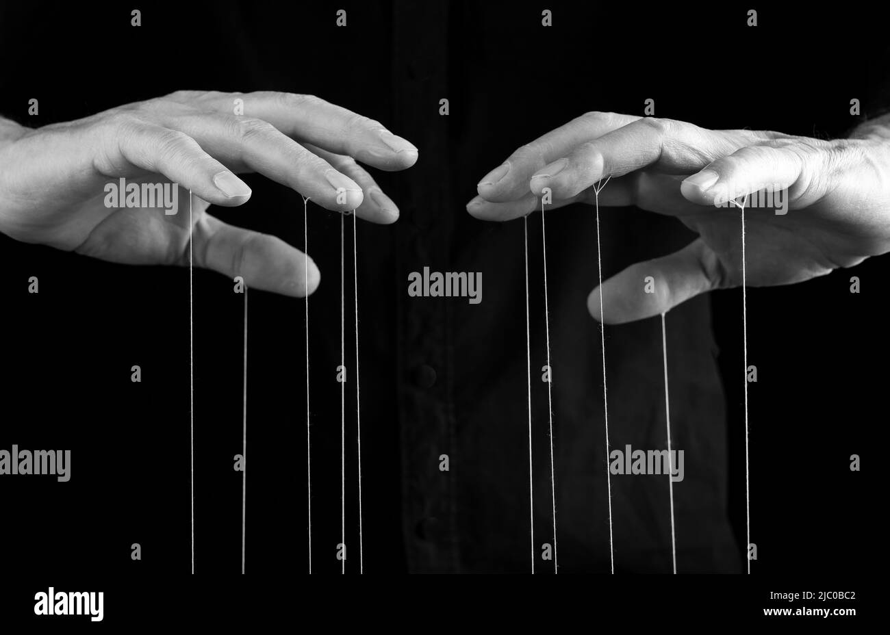 Mann Hände mit Saiten an den Fingern. Manipulation, Kontrolle, Macht, Missbrauch Konzept. Schwarz und Weiß. Hochwertige Fotos Stockfoto