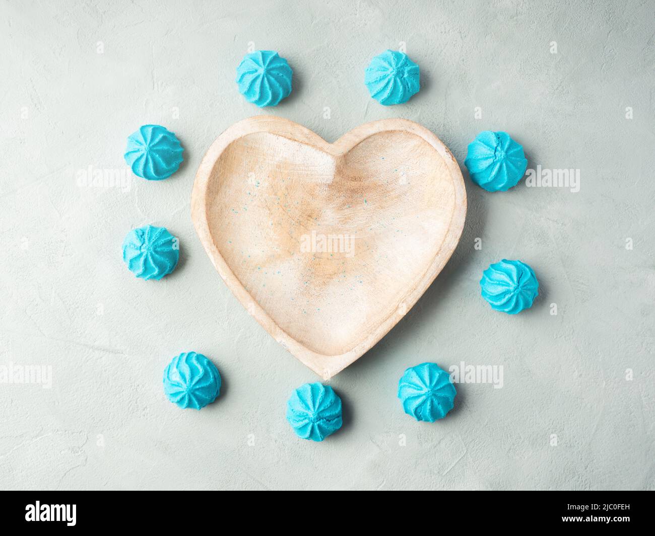 Herzförmige Holzschale mit blauen süßen Baisalgen, flach gelegt Stockfoto