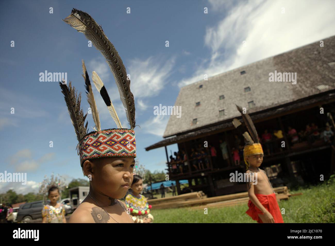 Kinder in traditioneller Trachtenanmutung stehen in der Schlange für eine Begrüßungszeremonie während einer Ökotourismus-Veranstaltung vor dem Langhaus der traditionellen Dayak IBAN-Gemeinde in Sungai Utik, Batu Lintang, Embaloh Hulu, Kapuas Hulu, West Kalimantan, Indonesien. Stockfoto