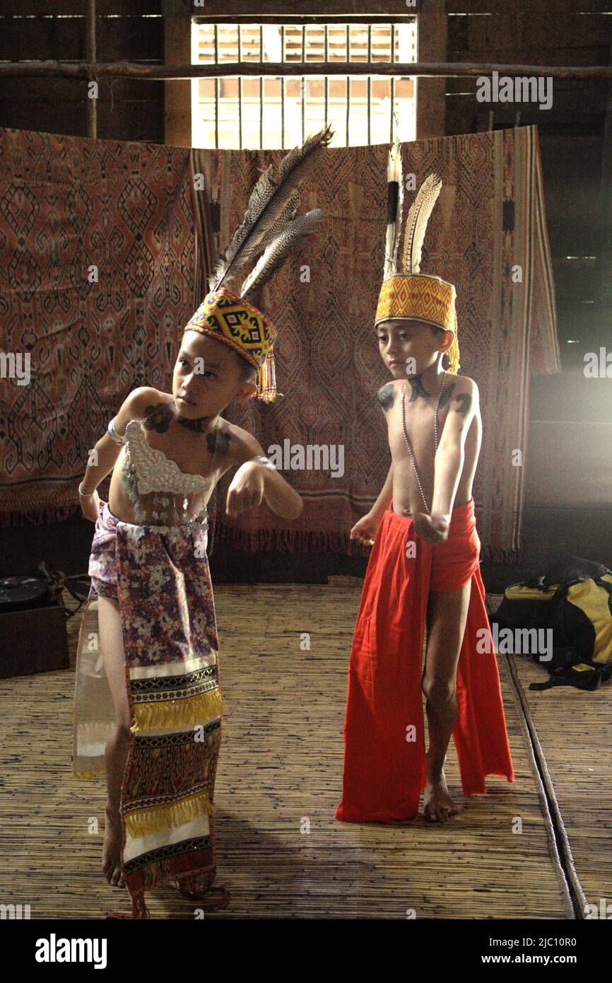 Kinder in traditioneller Trachtenkunst führen einen traditionellen Tanz während einer Ökotourismus-Veranstaltung im Longhouse der traditionellen Dayak IBAN-Gemeinde in Sungai Utik, Batu Lintang, Embaloh Hulu, Kapuas Hulu, West Kalimantan, Indonesien. Stockfoto
