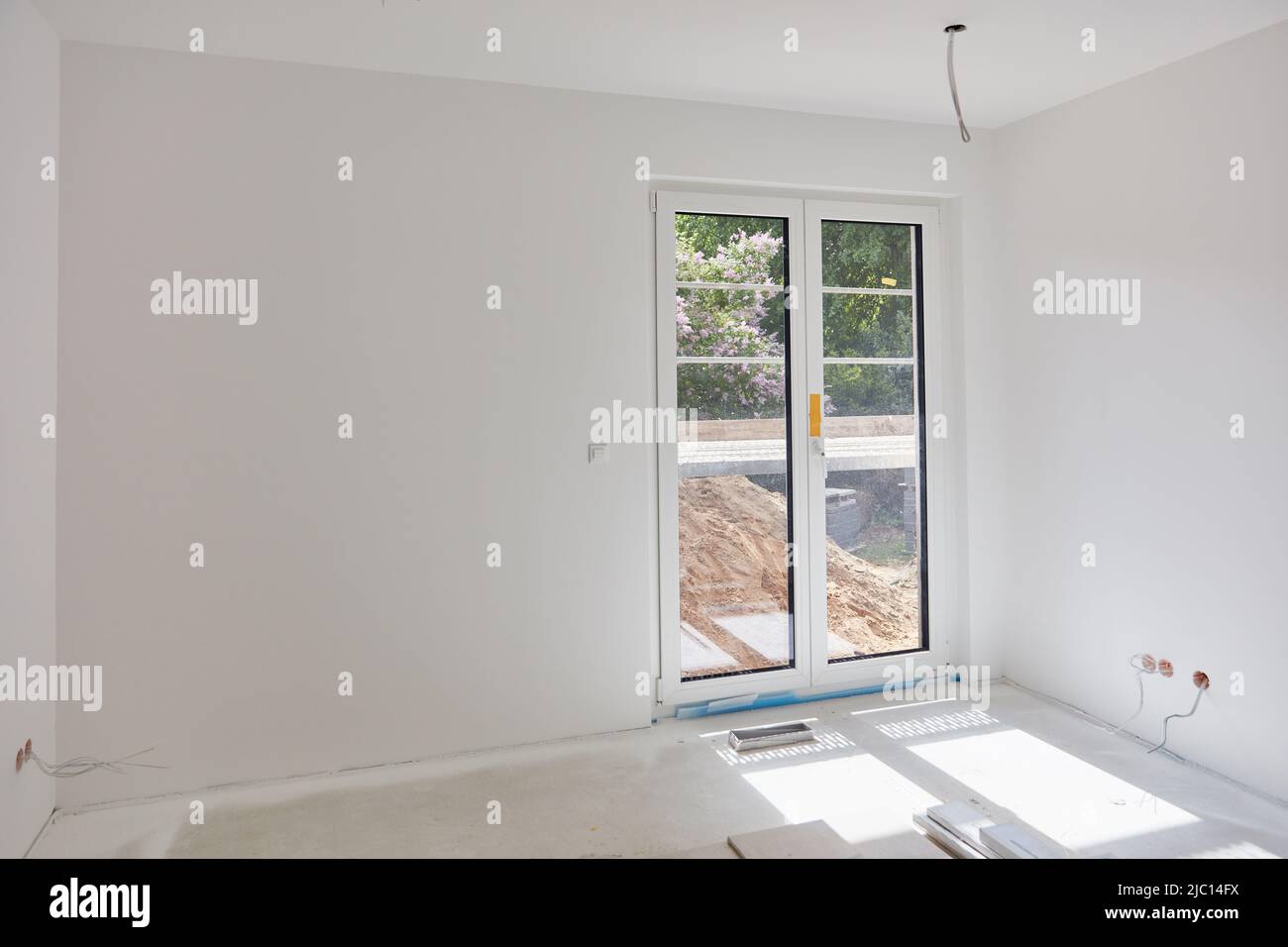 Weißes Zimmer mit einer Terrassentür nach dem Anstreichen in einem Neubau Stockfoto
