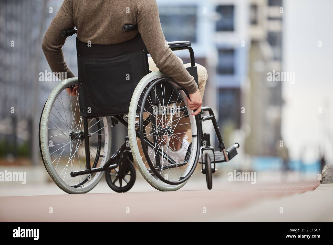 Nicht erkennbarer behinderter Mann in Freizeitkleidung, der aufgrund von Beinproblemen Hilfsgeräte für die persönliche Mobilität verwendet Stockfoto