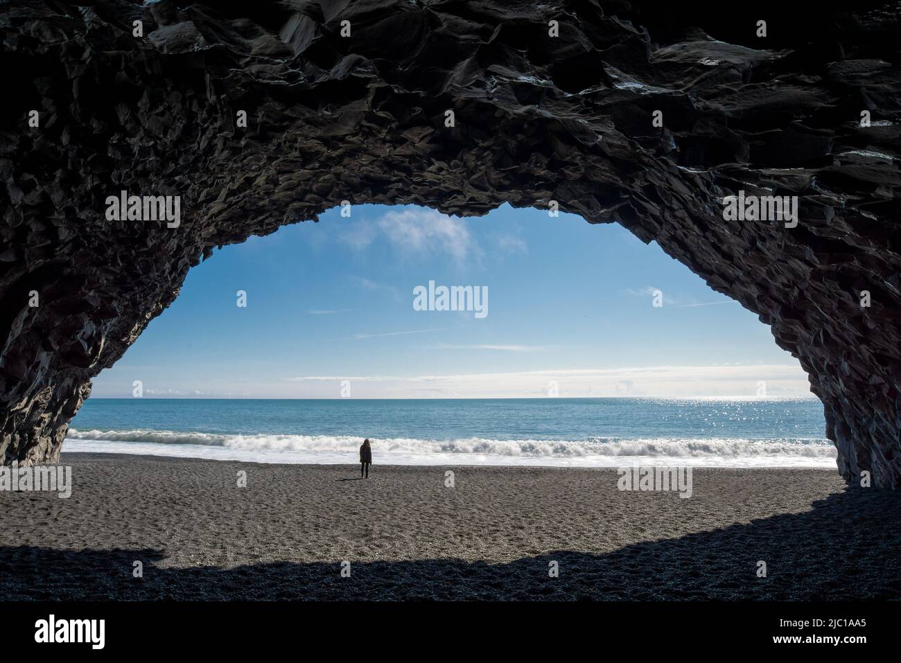 Frau, die in einer Basaltsteinhöhle am Strand von Reynisfjara in Island steht Stockfoto