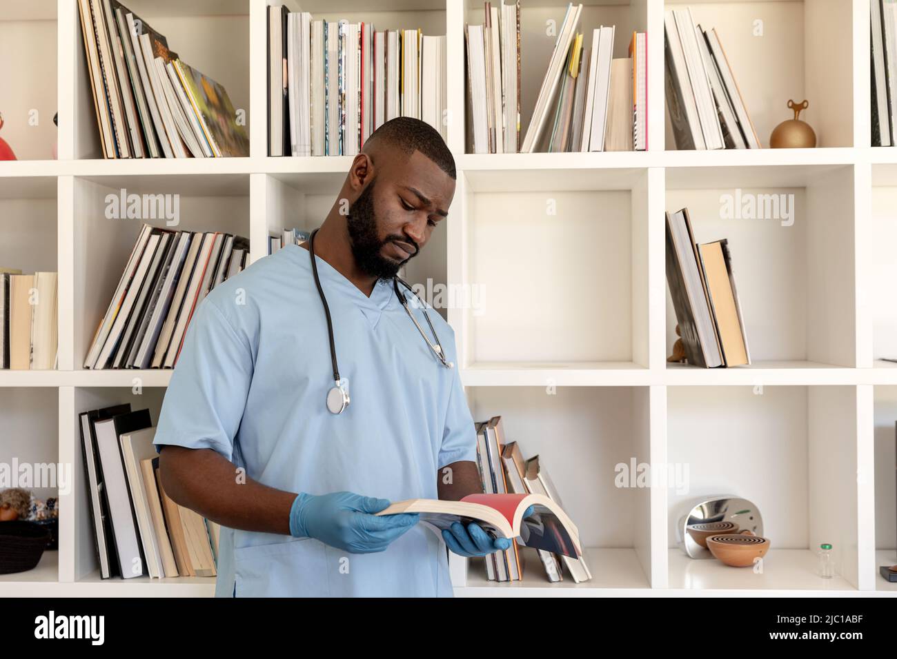 afroamerikanischer männlicher Gesundheitshelfer, der zu Hause im Wohnzimmer ein Buch liest Stockfoto