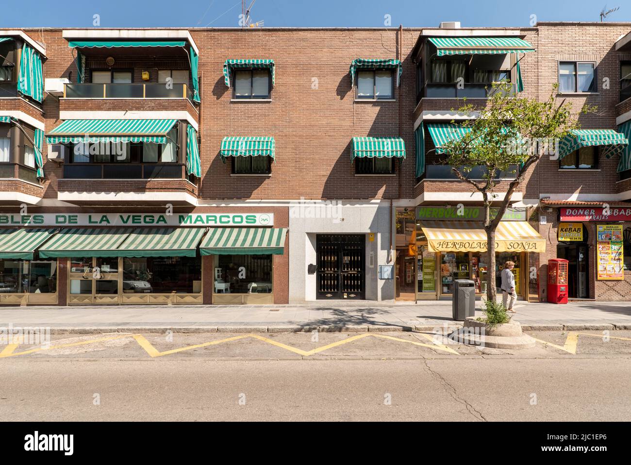 Straße mit dreistöckigen Häusern mit Markisen auf den Terrassen und Geschäftsräumen im Erdgeschoss Stockfoto
