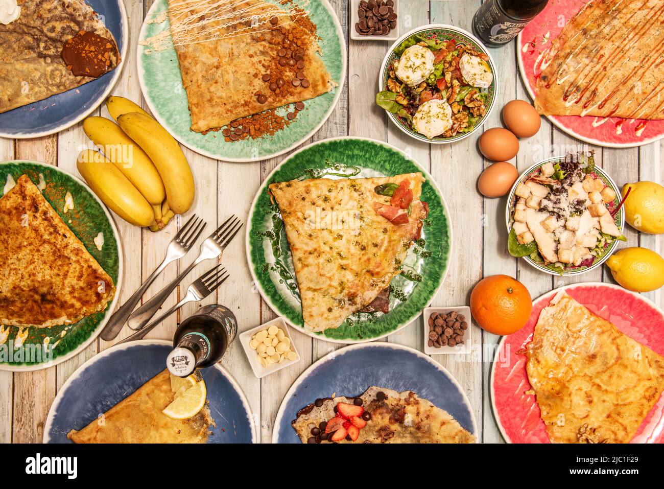 Set aus herzhaften und süßen französischen Pfannkuchen, Salat mit Croutons und Salat mit Ziegenkäse, Obst, Eiern und Orangen und Zitronen Stockfoto