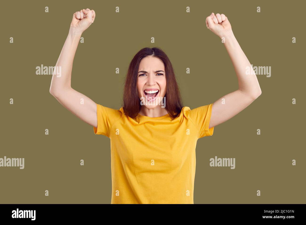 Verrückte glückliche Frau freut sich aufrichtig über ihren Erfolg und Triumph auf khaki Hintergrund. Stockfoto