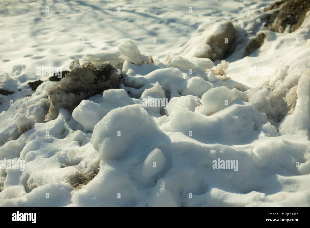 Schnee von der Straße entfernt. Schneehaufen draußen. Dreckiger Straßenrand. Eisblöcke. Stockfoto