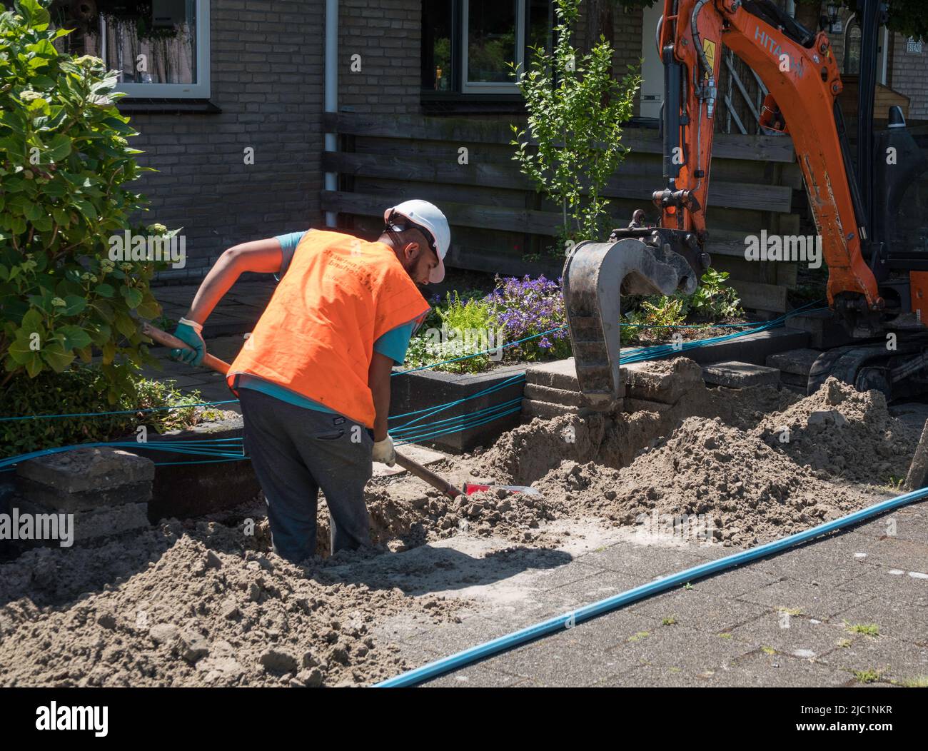 Mann gräbt einen Graben für den Bau von Glasfaser Stockfoto