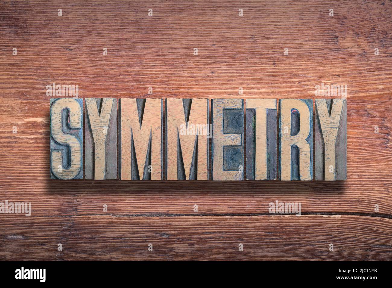 Symmetriewort aus Vintage-Buchdruck auf lackierter Holzoberfläche kombiniert Stockfoto
