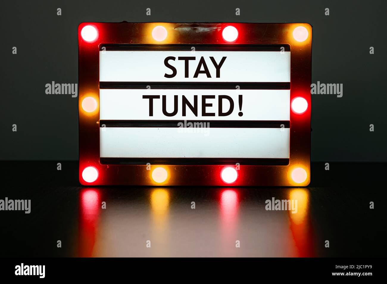 Lightbox mit roten und orangen Lichtern im dunklen Raum mit Worten - Stay tuned! Stockfoto