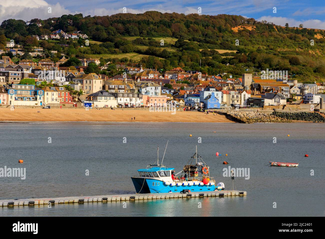 Ein Fischerboot, das an einem Ponton vor dem Hafen von Lyme Regis an der Jurassic Coast mit der Stadt dahinter festgemacht ist, Dorset, England, Großbritannien Stockfoto