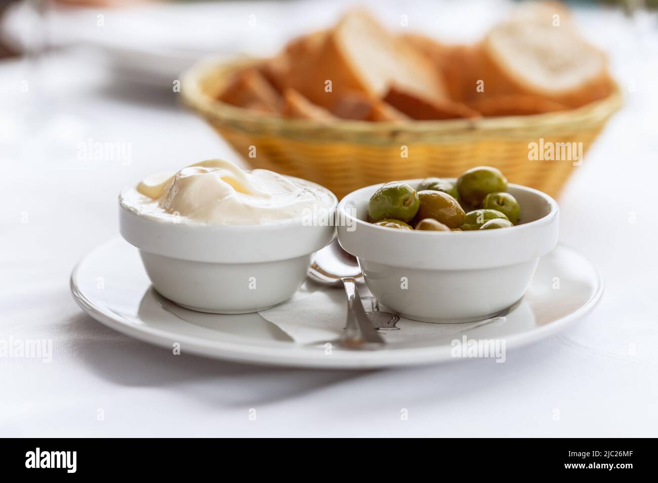 Klassische spanische Vorspeise Alioli (hausgemachte Knoblauch-Mayonnaise) mit grünen Oliven und hausgemachtem Brot Stockfoto
