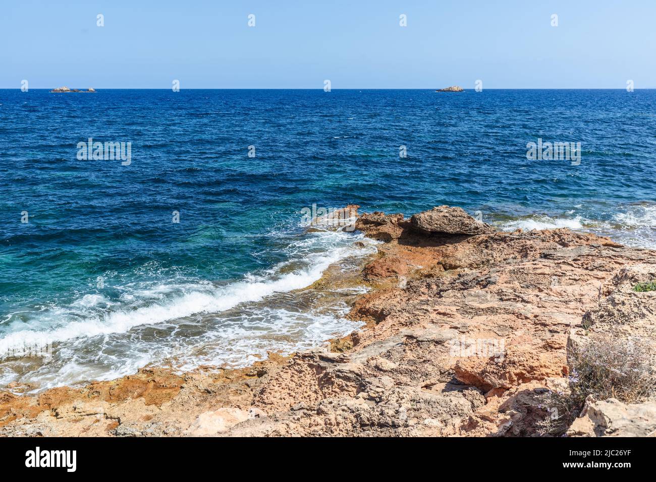 Vom Meerwasser ausgewaschen und von Sonne und Wind getrocknet, sanfte Küste der Insel Ibiza, kleine Wellen auf der Wasseroberfläche, Balearen, Spanien Stockfoto