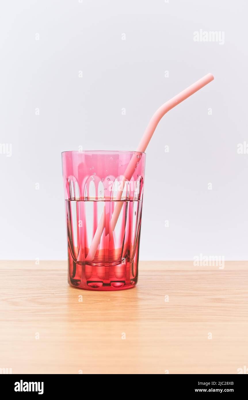 Glas frisches Wasser und Trinkhalm auf einem hellen Holztisch Stockfoto