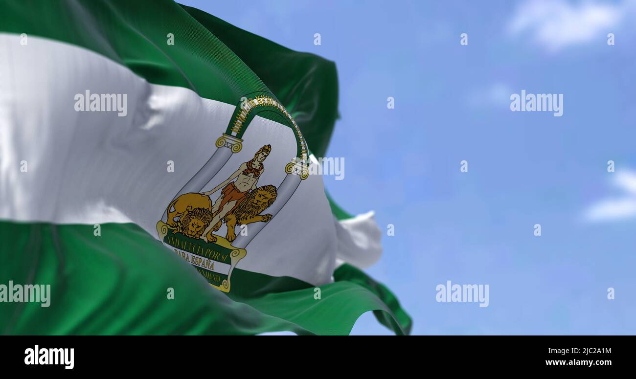 Andalusische Flagge winkt an einem klaren Tag im Wind. Andalusien ist die südlichste autonome Gemeinschaft auf der Halbinsel Spanien, die bevölkerungsreichste und die s Stockfoto