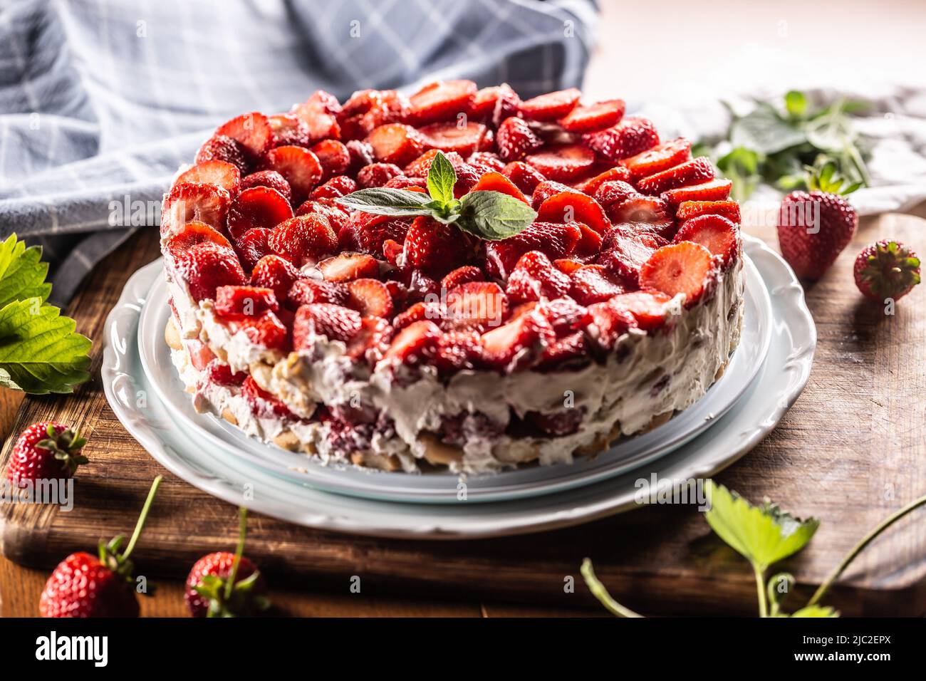 Erdbeer-Sahnetorte mit Biskuitkuchen auf einem weißen Teller. Stockfoto