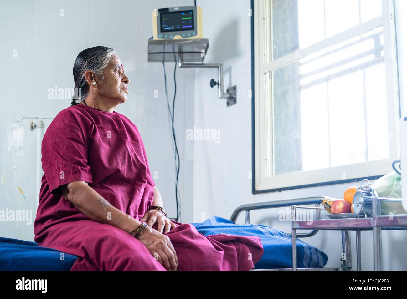 Handgeführte Aufnahme von älteren kranken Frauen, die vor der Operation auf dem Bett im Krankenhaus saßen und tiefes Denken vorbrachten - Konzept der Krankheit, der Sorge und der Medicare. Stockfoto