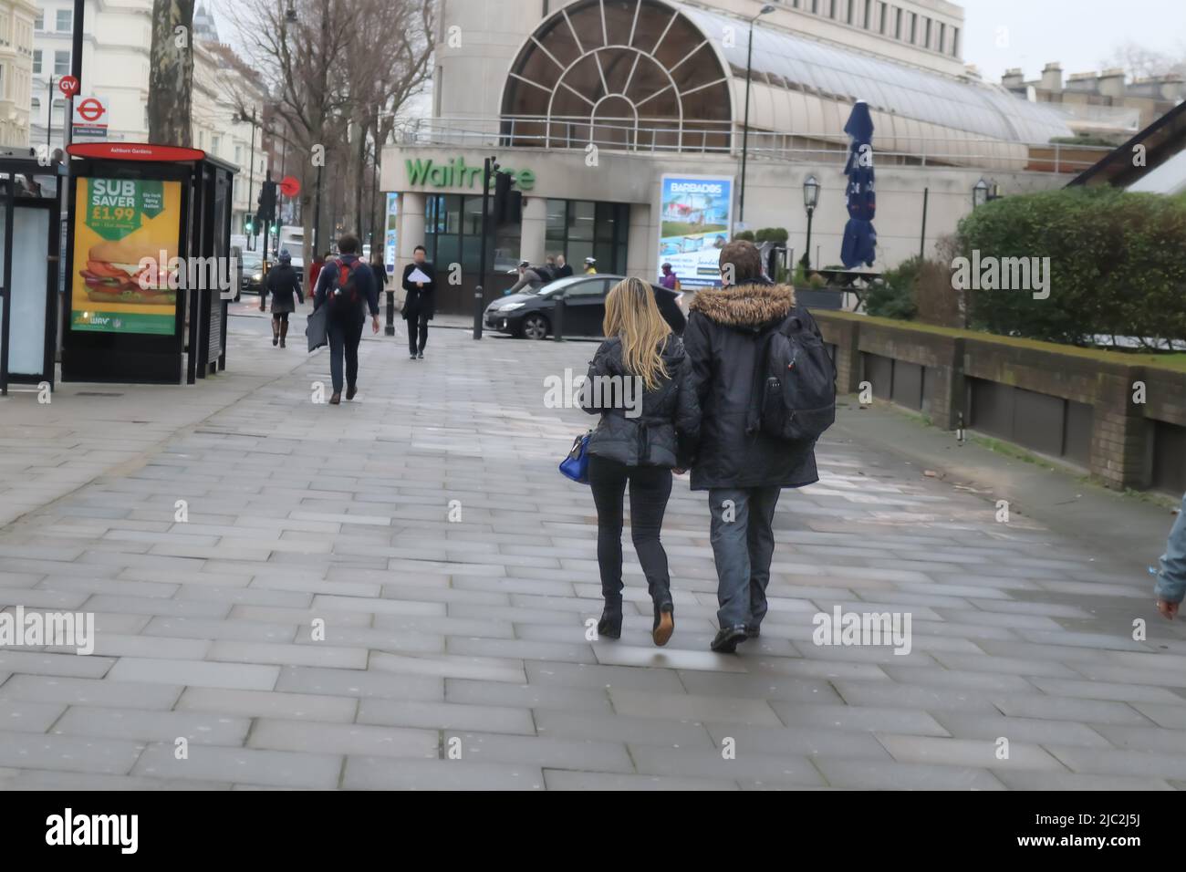 2018 01 10 London UK Mann und Frau mit langen blonden Haaren, beide in Wintermänteln gekleidet, mit einem Rucksack, gehen von der Kamerastraße weg Stockfoto