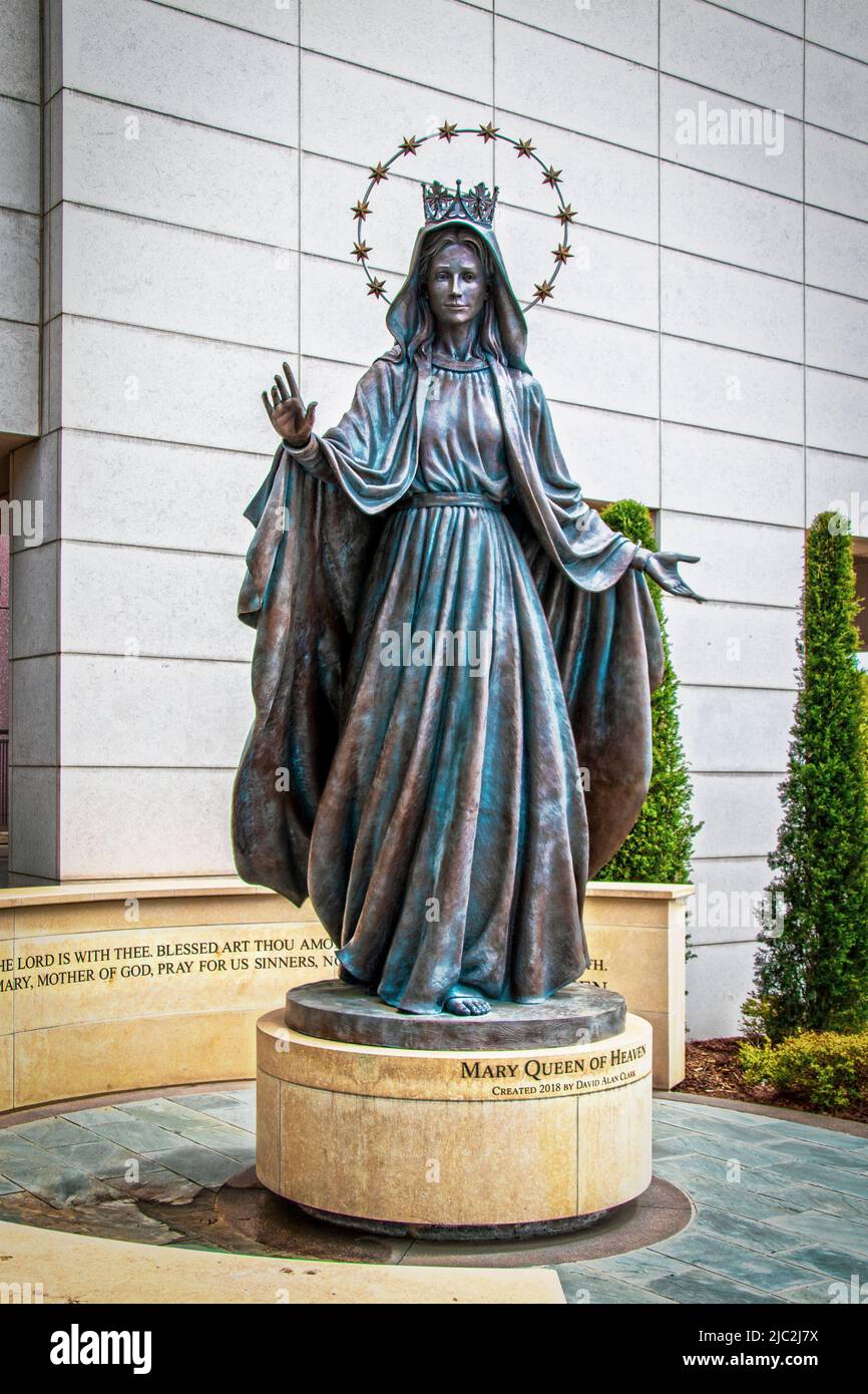 2022 04-21 Tulsa USA - Mary Queen of Heaven Statue auf rundem Sockel vor dem St. Francis Hospital, teilweise umgeben von Felswänden und Zypressen Stockfoto