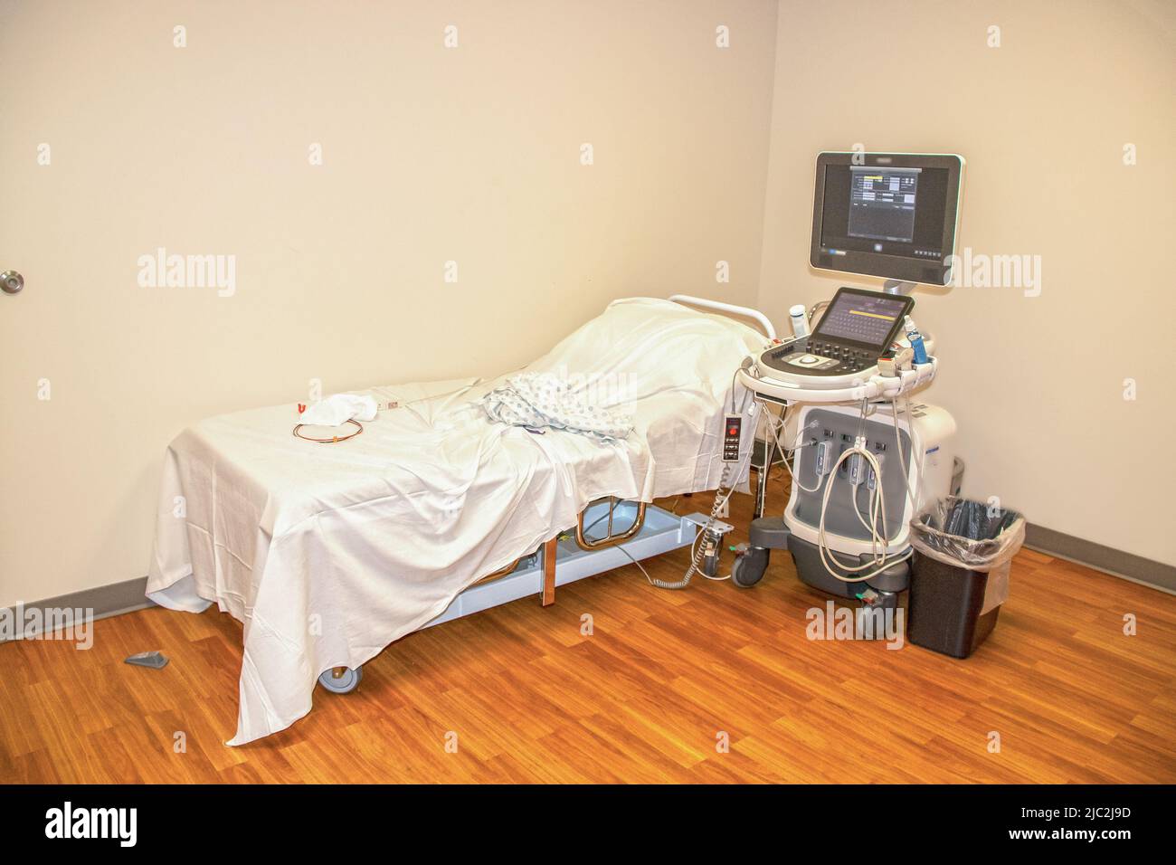 Ein Bett und eine Maschine, um einem Herzpatienten ein Echokardiogramm zu geben - Krankenhausmantel und Elektroden und Drähte, die auf dem Bett liegen Stockfoto