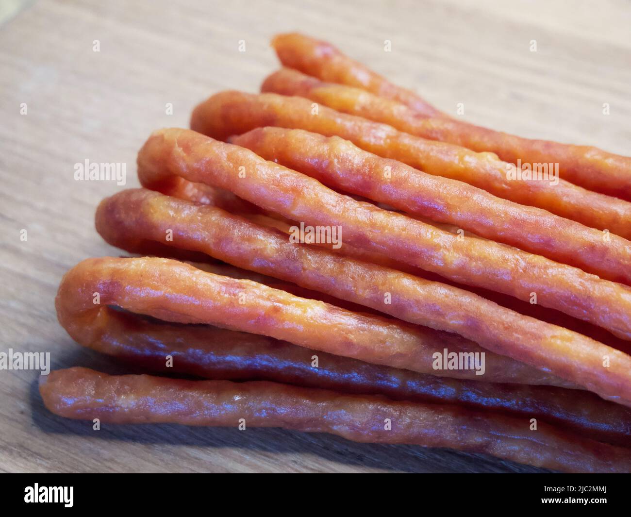 Traditionelle polnische Würste Kabanos auf einer hölzernen Oberfläche, Makrofoto. Kabanos, auch bekannt als Cabanossi oder Kabana, ist in der Regel eine lange, dünne, trockene Wurst Stockfoto