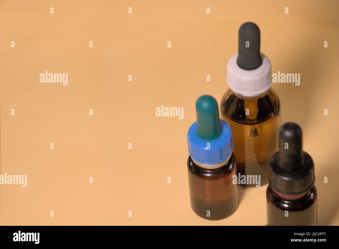 Braune Flaschen mit Droppern, ohne Branding, Textraum, gelblicher Hintergrund. Stockfoto