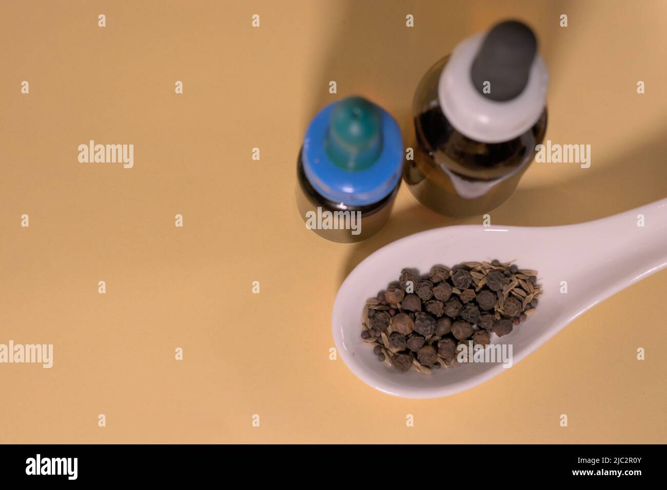 Braune Tropfflaschen mit Kräutern oder Gewürzen auf weißem Löffel, ohne Branding und mit korrekter Textfläche. Stockfoto