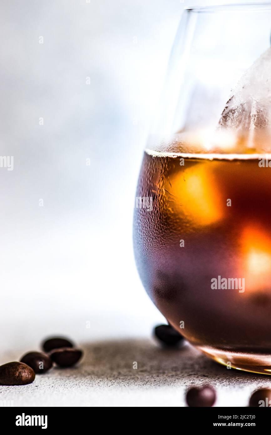 Nahaufnahme eines eisgekühlten Kaffeegetränks auf einem Tisch mit gerösteten Kaffeebohnen Stockfoto