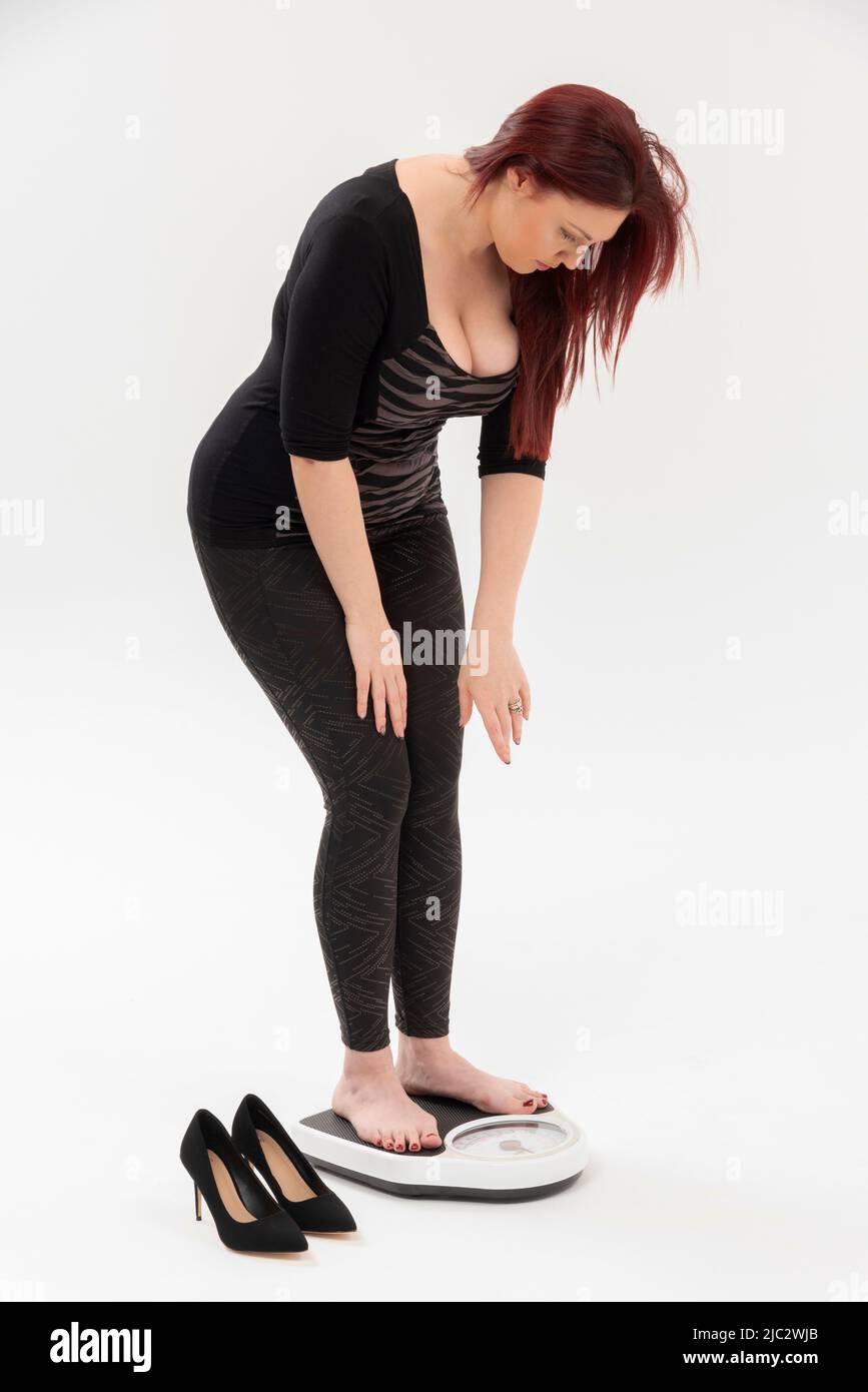 Wiltshire, England, Großbritannien. 2022. Frau, die ein Set von Badezimmerwaagen benutzt, um ihr Gewicht zu überprüfen. Stockfoto
