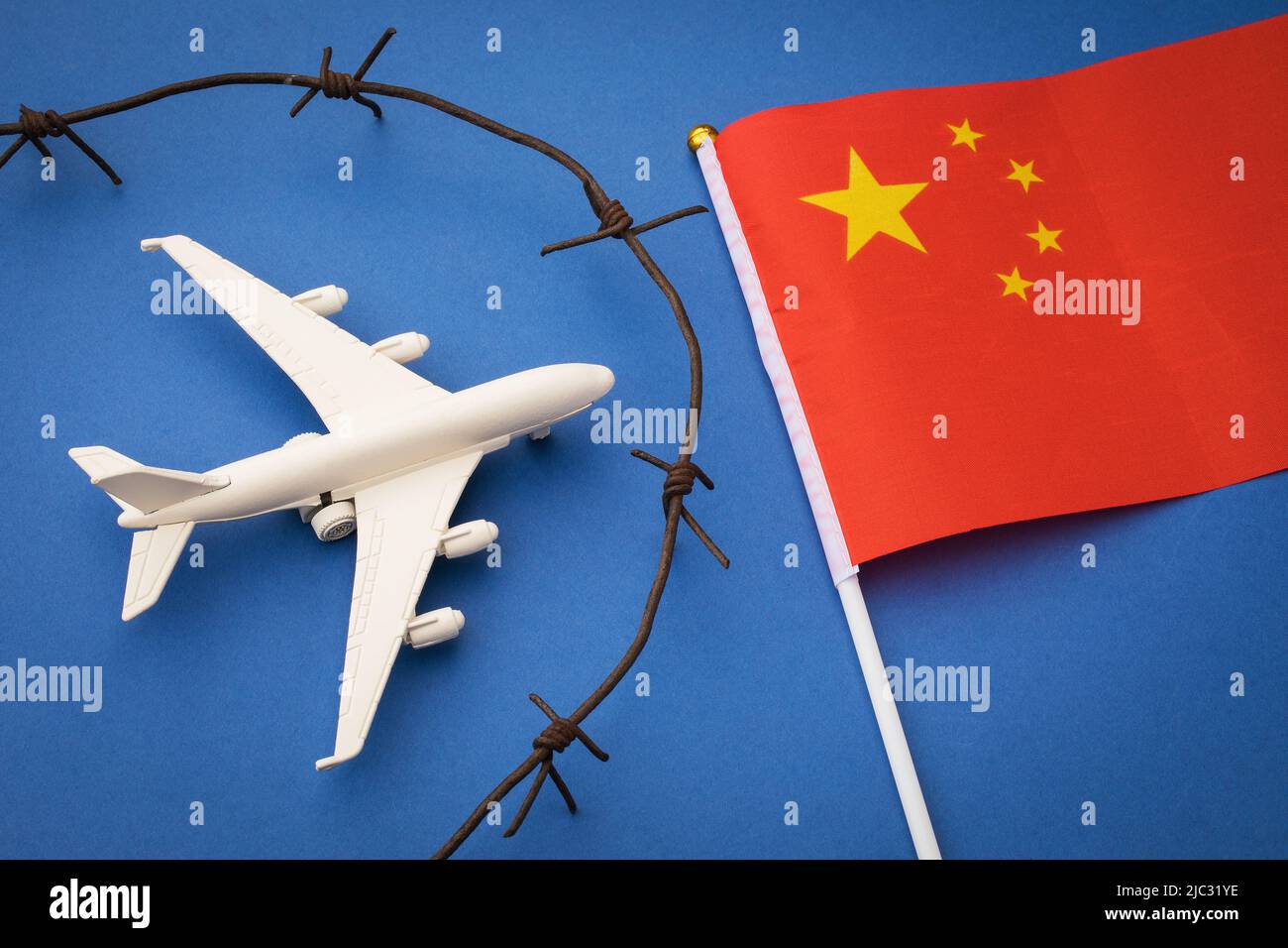 Spielzeugflugzeug, Flagge und rostiger Stacheldraht auf farbigem Hintergrund, China Air Border geschlossenes Konzept Stockfoto