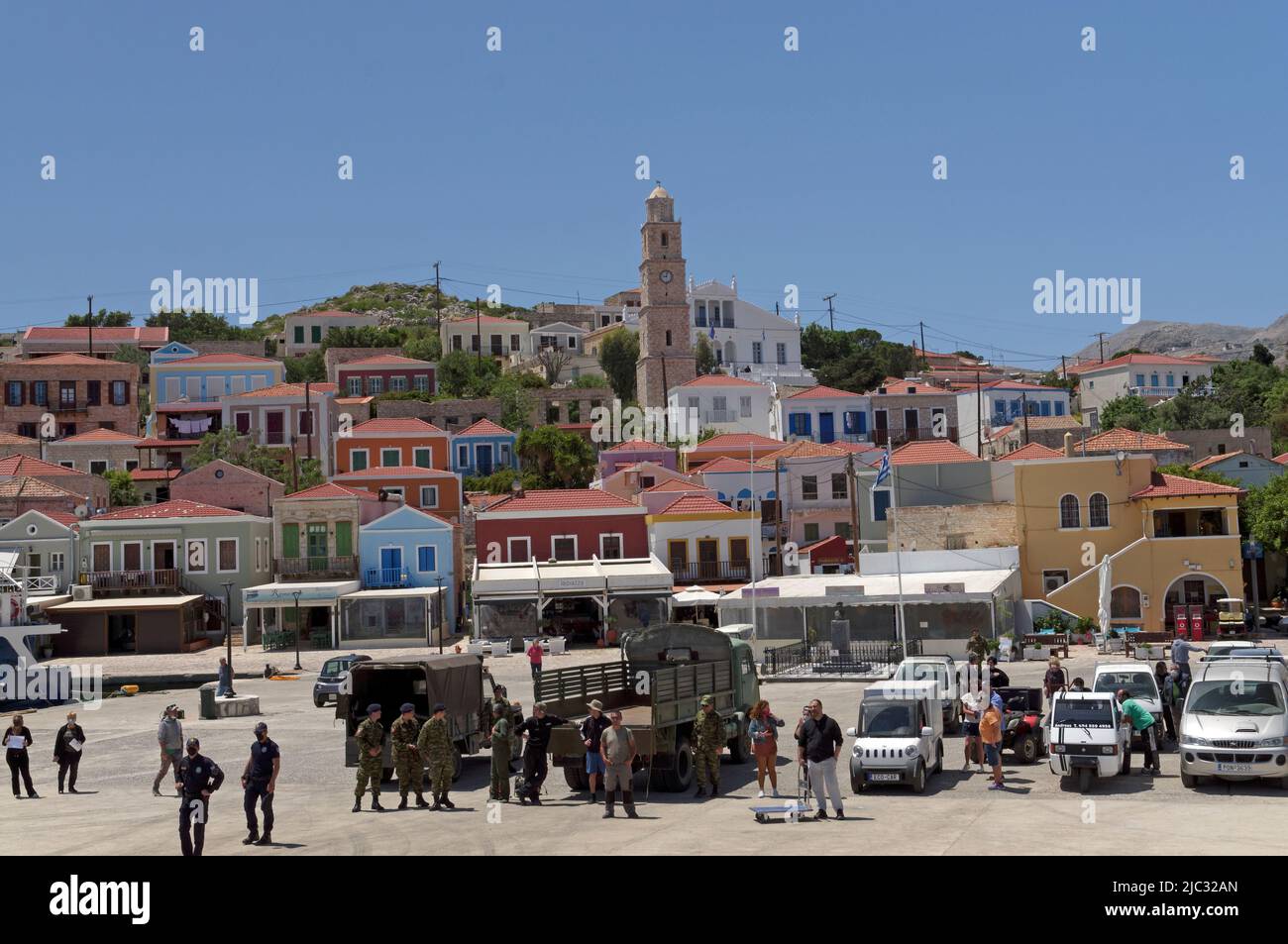 Blick von der Dodecanese Express Fähre zur Insel Halki, in der Nähe von Rhodos. Soldaten und Touristen am Hafen. Stockfoto
