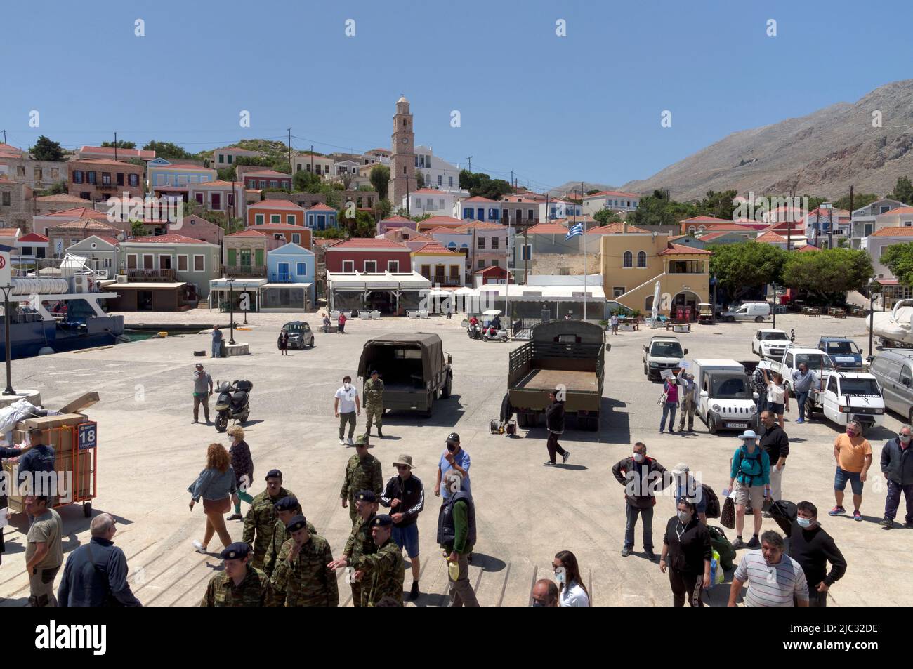 Blick von der Dodecanese Express Fähre zur Insel Halki, in der Nähe von Rhodos. Soldaten und Touristen am Hafen. Stockfoto