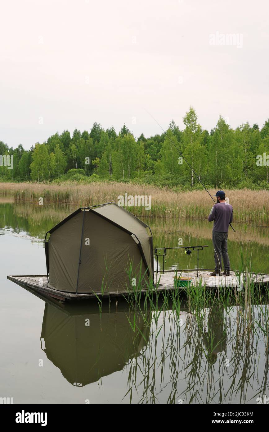 Mann, der mit dem Zelt am Ufer des Sees angeln kann. Survival concept.authentic Reise, vertikale Ansicht Stockfoto