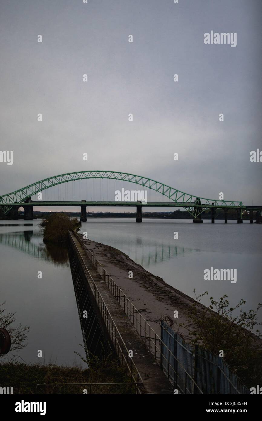 Runcorn Bridge / Silver Jubilee Bridge in Runcorn, Großbritannien, reflektiert im Wasser. Stockfoto