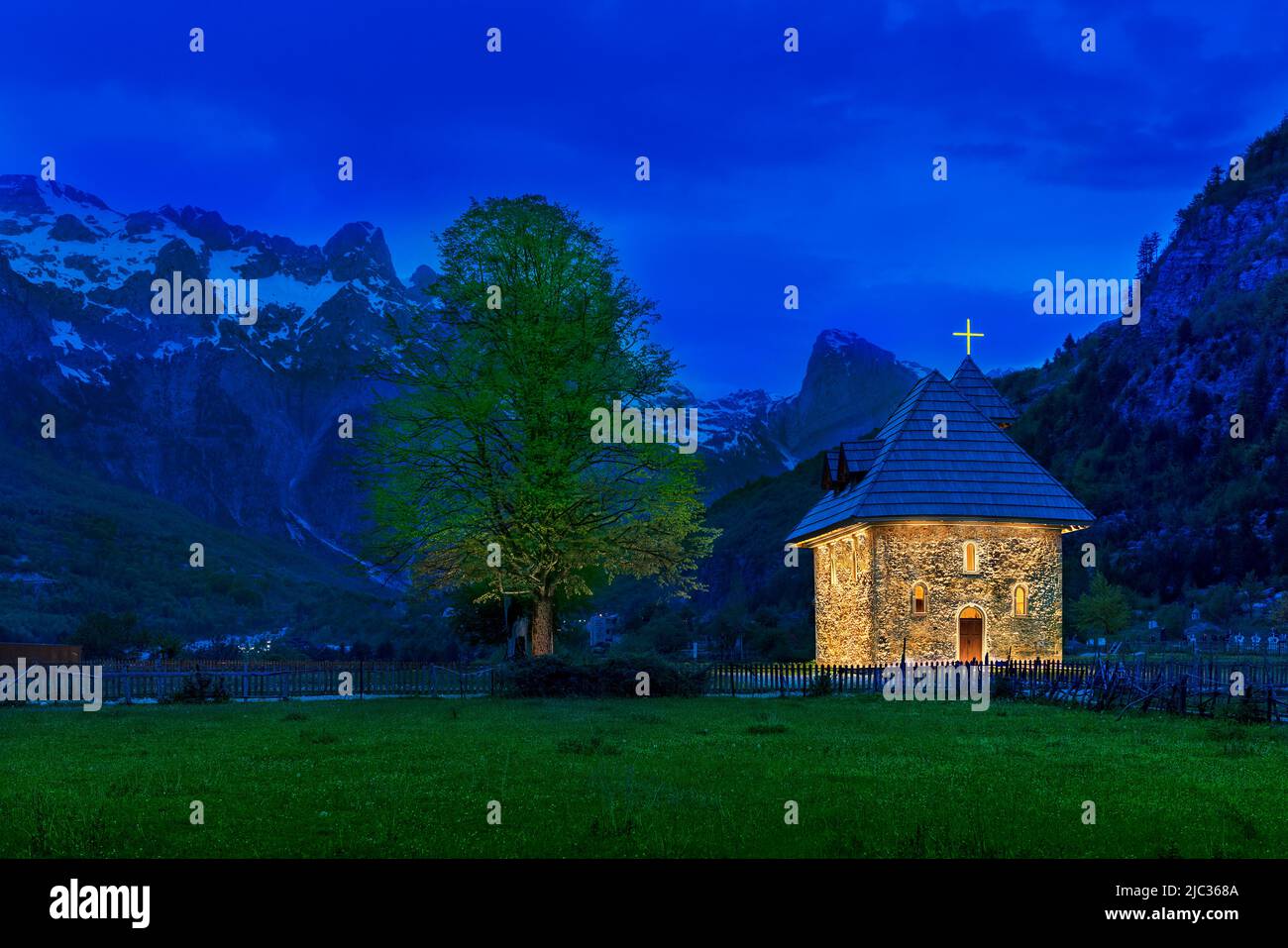 Kirche im Thethischen Dorf und schneebedeckte Berge, in der Abenddämmerung, im Theth-Tal, Albanien. Stockfoto