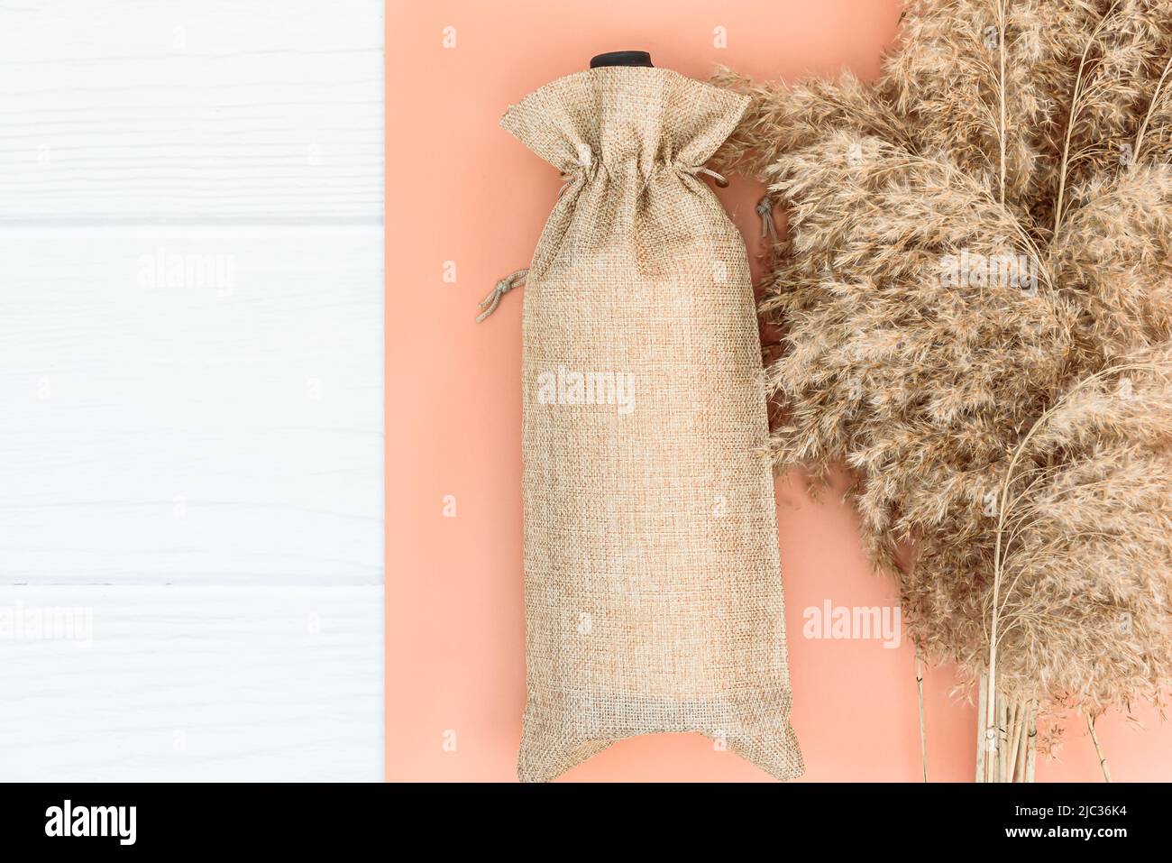 Herbstmockup mit Weinbeutel blank und trockenem Schilf auf weißem Holz Hintergrund. Stockfoto