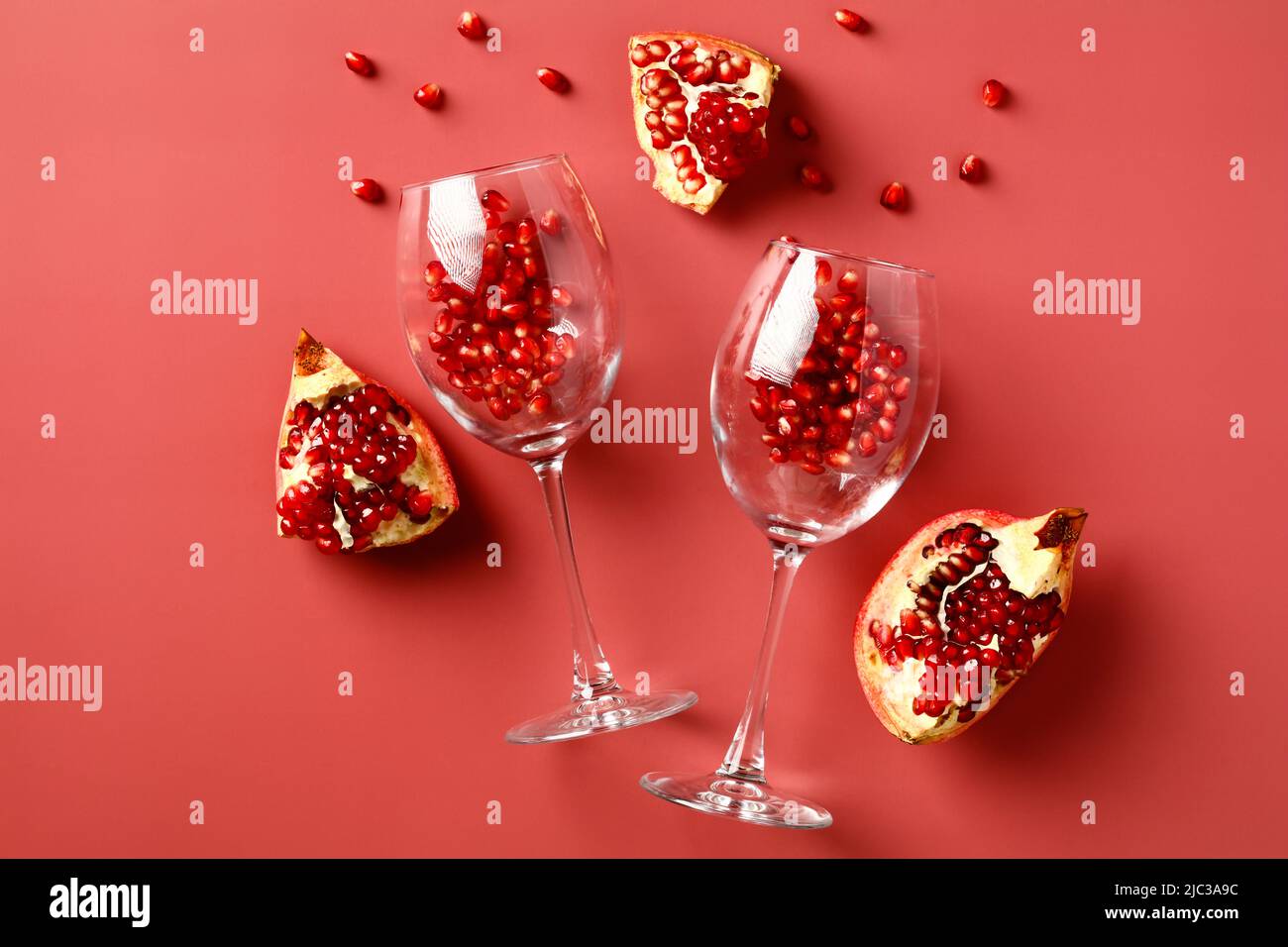 Weingläser mit Granatapfel auf rotem Hintergrund. Flach liegend, Draufsicht. Stockfoto