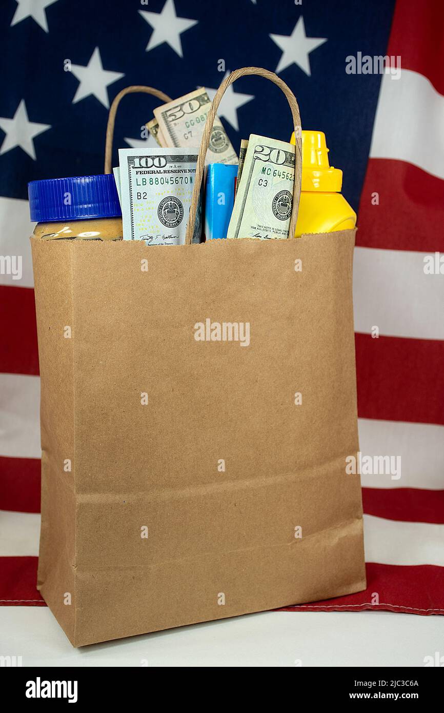 Eine einfache braune Papiertüte, gefüllt mit Lebensmitteln und Geld auf einer amerikanischen Flagge Stockfoto