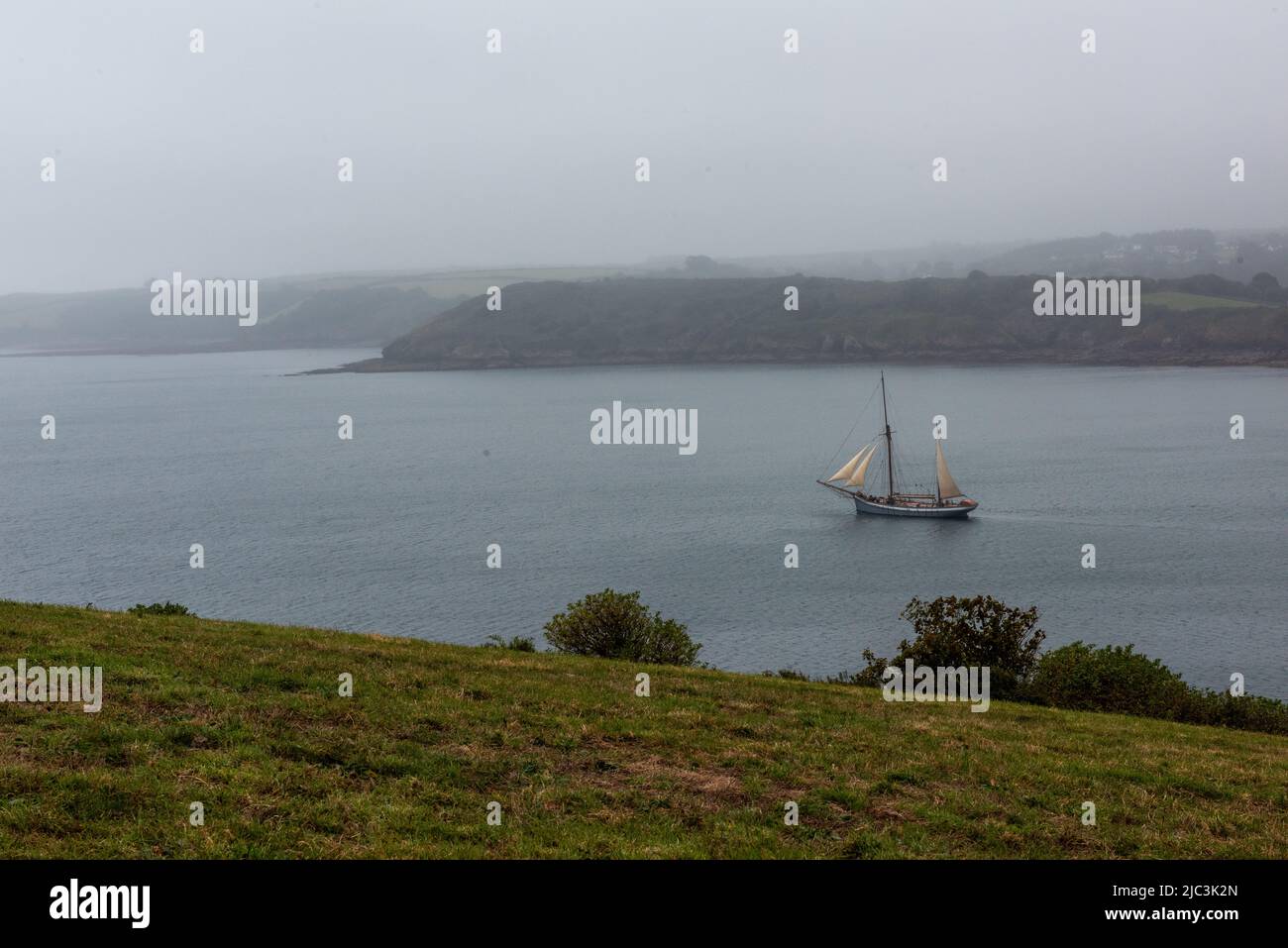 Neblige Aussicht mit Segelboot Stockfoto