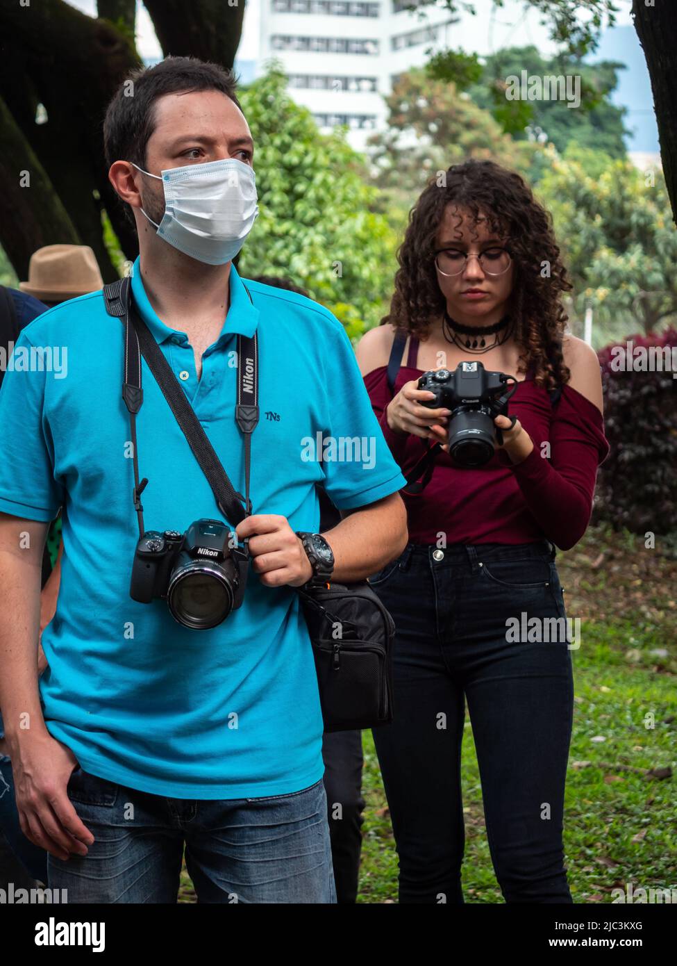 Medellin, Antioquia, Kolumbien - Februar 19 2022: Zwei junge Kolumbianer machen Fotos in einem wunderschönen Garten voller Bäume Stockfoto